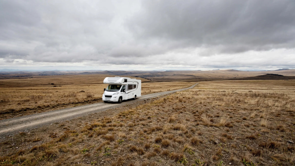 Camping-car seul sur une route traversant un vaste plateau désert